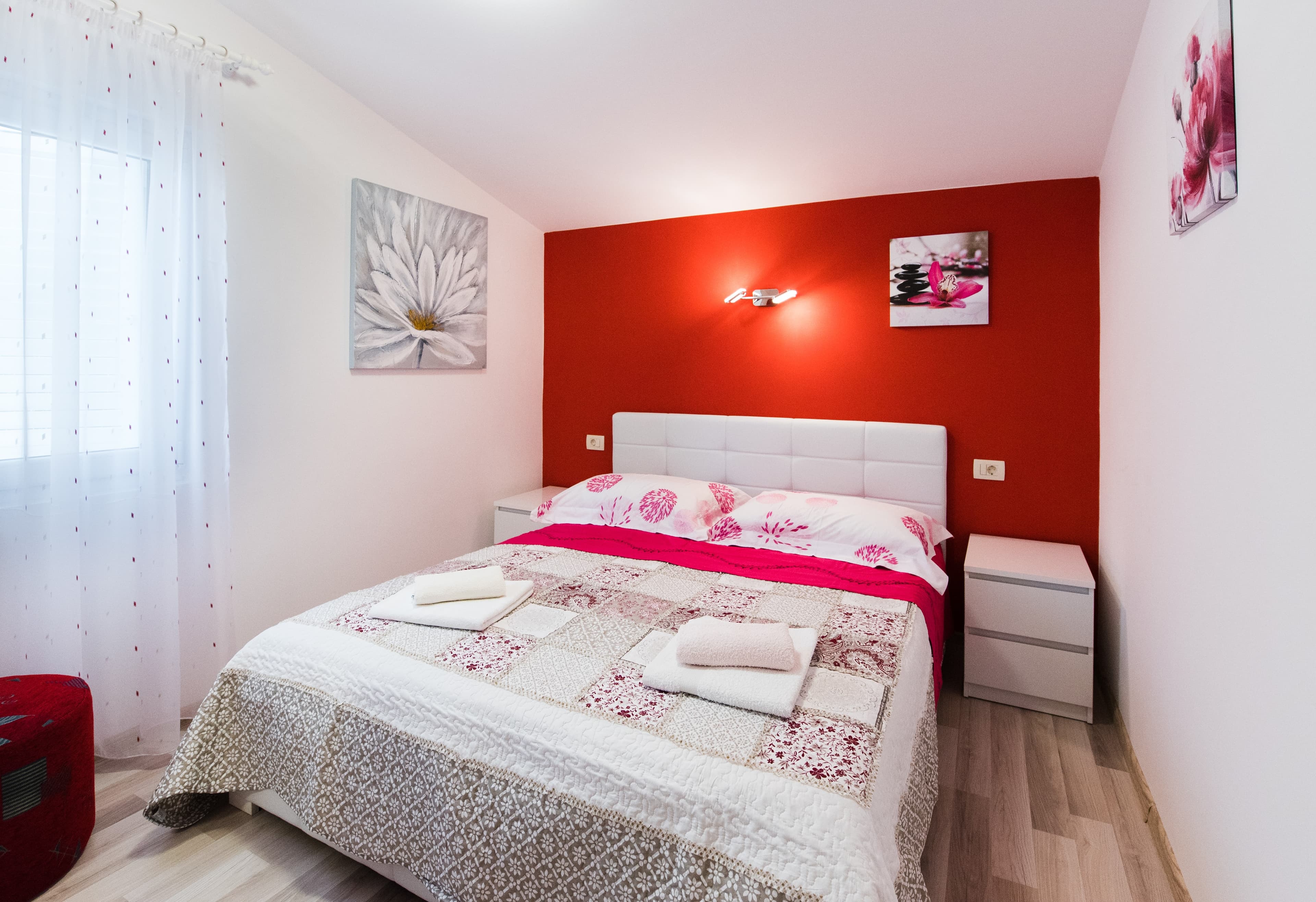 Bright bedroom with red accent wall and white furnishings