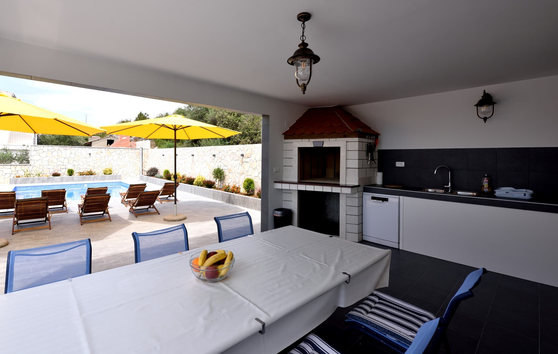 Covered outdoor kitchen with grill overlooking the pool